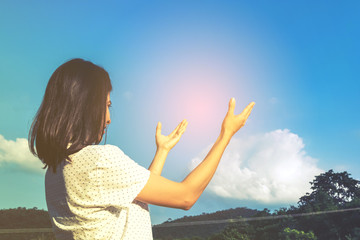 pretty young asian girl standing and pray to blue sky
