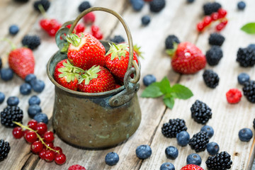 Close-up of strawberries in an antic pail on wooden table full with strawberries