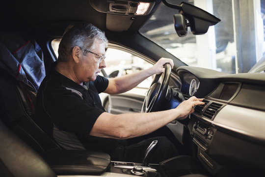 Side view of senior worker examining air conditioner while sitting in car