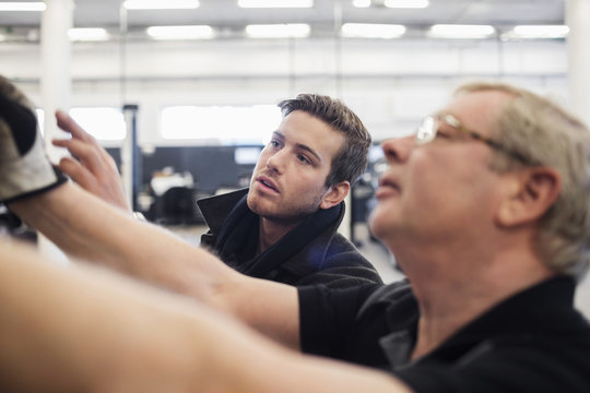 Close-up of senior mechanic discussing with client at auto repair shop