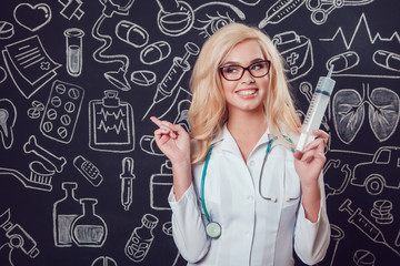 Beautiful blonde woman doctor in glasses and white coat holding syringe on dark background with pattern