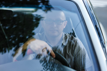 man with glasses sitting behind the wheel of a car