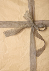 A gift wrapped in brown paper with rustic bow, forming a page background texture