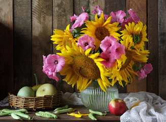 Fototapeta premium Bouquet of sunflowers in pitcher, pumpkin, peas and an Apple on