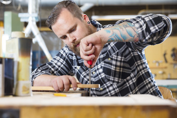 Obraz premium Craftsman files wooden guitar neck in workshop