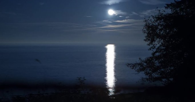 Tongue Point, Washington, USA - moonlight and its reflection in the ocean on the coast of the Tongue Point at clear night with few clouds - Timelapse with pan right to left
