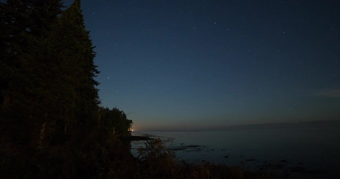 Tongue Point, Washington, USA - clear starry night with moonlight and moving shadows over the coast of Tongue Point with ferries at the ocean - Timelapse with pan left to right