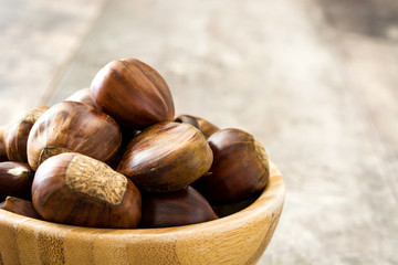 Chestnuts in a bowl on wooden background
