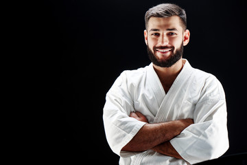Portrait of a smiling man in karate kimono on black background © amixstudio