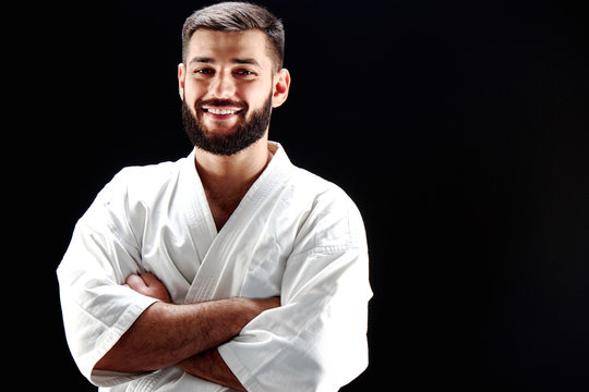 Portrait of a smiling man in karate kimono on black background