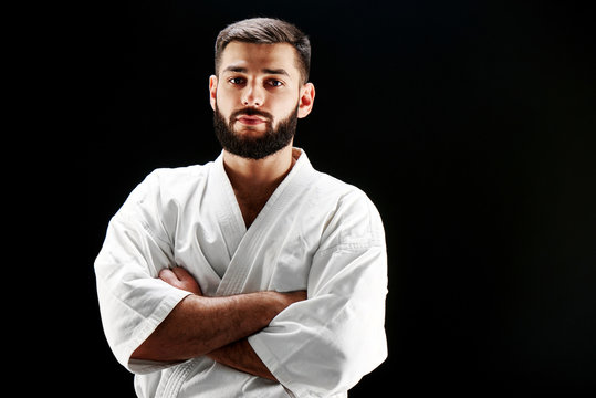 Portrait of a karate man with a beard in a kimono against a black background
