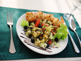 Greek salad on a white plate. Served on a table with a green tablecloth in a restaurant