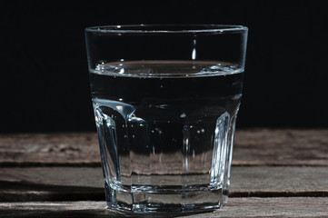glass of clear water on the wooden textural background