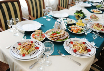 Set the table in the restaurant. Bright interior. Salads and snacks
