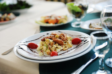 Salad with chiken on a white plate. Served on a table with a green tablecloth in a restaurant