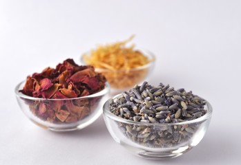 Dried flowers of marigold (calendula), lavender and rose for beauty treatments in clear glass bowls 