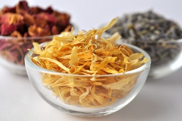 Dried flowers of marigold (calendula), lavender and rose for beauty treatments in clear glass bowls 