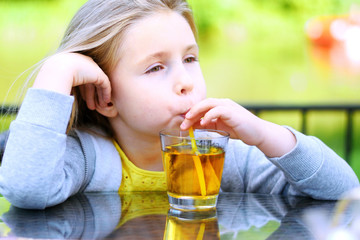 Adorable little girl drinking apple juice in cafe