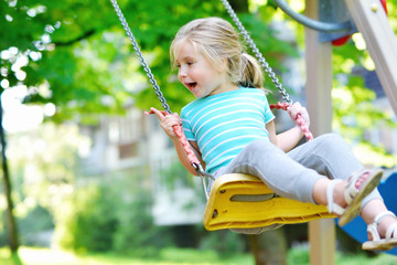 Adorable girl having fun on a swing on summer day