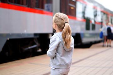 Fototapeta premium Little girl waiting for train on railway station platform