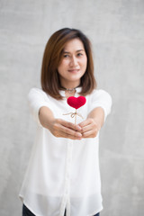 Giving love gift, Asian woman hand hold give beautiful red heart sweet loving symbol of take care or charity help to you.