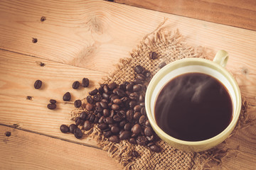aroma hot black coffee or Americano and Arabica coffee bean with smoke on wood background.