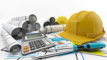 Planos enrollados para la construcción de una casa junto a un casco de protección, una calculadora y etiquetas de eficiencia energética. Reformas.