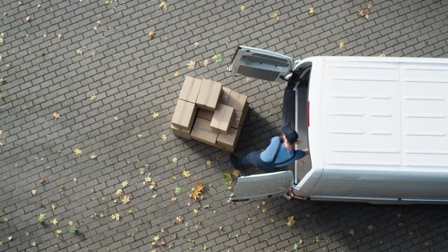 Delivery Man Loads his Commercial Van with Cardboard Boxes.