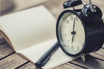 retro clock time at 6 o'clock with notebook or memo on wood table, times of memory writing diary...