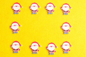 Santa figurines forming a border on a yellow background