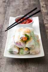 Vietnamese rolls with vegetables, rice noodles and prawns on wooden background

