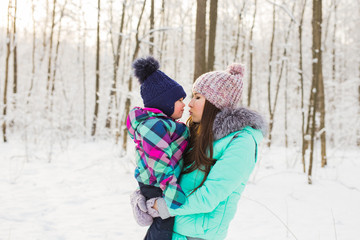 Fototapeta na wymiar Young brunette mother with her daughter outdoors. Winter time