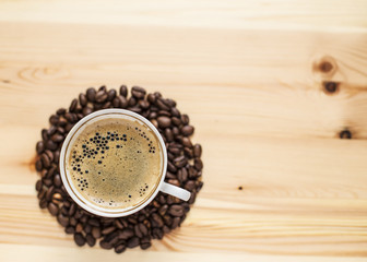 Appetizing cup of coffee and grain lying on the wooden table