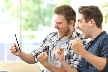 Excited friends watching tv on a tablet