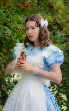 girl in image of fairy tale heroine drinks drink of glass bottle