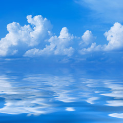 Plakat Clouds in the bright blue sky are reflected in a surface of wate