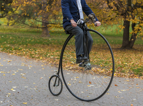 Fototapeta Penny-farthing bicycle in a park, unidentified man riding a vintage bike in a park