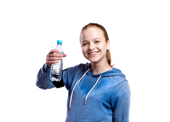 Teenage girl holding water bottle. Studio shot, isolated.