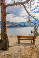 Female tourist at the bench over fantastic lake view in Canada.