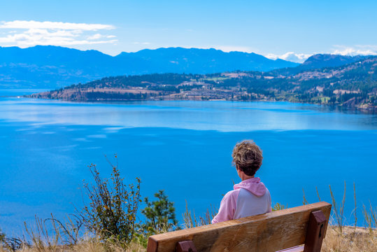 Female Tourist At The Bench Over Fantastic Lake View In Canada.