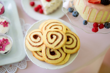 Spiral cookies, cake and cupcakes laid on table.