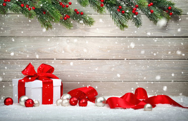 Weihnachten Holz Hintergrund mit Geschenk und rotem Band, Kugeln, Tannenzweigen und Schnee