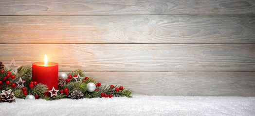 Weihnachten oder Advent Hintergrund: Holz, eine Kerze und Tannenzweige auf Schnee, Panorama Format...