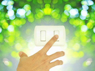 Man hand turn off light switch on green nature bokeh background, Eco friendly concept, Green concept, Save energy concept