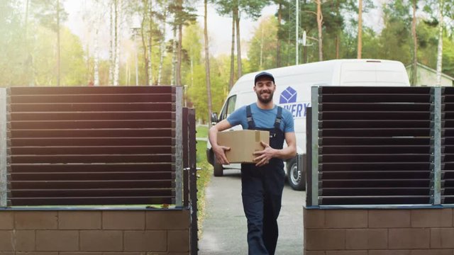 Smiling Delivery Man Comes Towards the House with Package. Cargo Van and Sunny Autumn with Yellow Birches and Pines is on the Background. Shot on RED Cinema Camera in 4K (UHD).