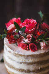 Appetizing wedding cake with flowers in rustic style on dark background