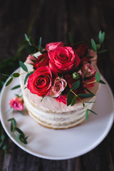 Obraz na płótnie Canvas Appetizing wedding cake with flowers in rustic style on dark background