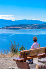 Female tourist at the bench over fantastic lake view in Canada.