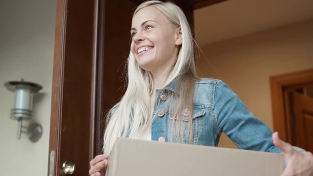 Smiling Homeowner Receives Postal Parcel and Signs Electronic Signature Deivce. While Standing in the Open Doorway. Shot on RED Cinema Camera in 4K (UHD).