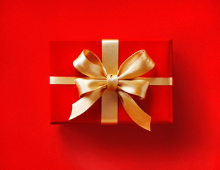 Gift box with golden ribbon on red background. Close up. Top view. High resolution product